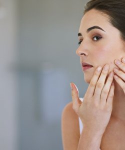 Woman checking her skin in a mirror